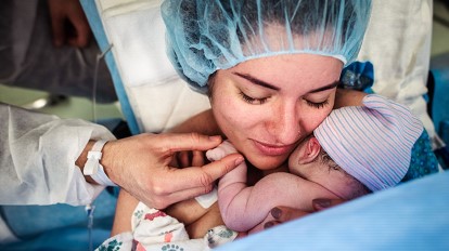 Woman holding newborn baby after in Caesarean