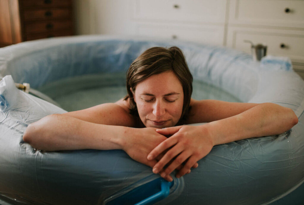 Woman leaning on the side of a birth pool at home