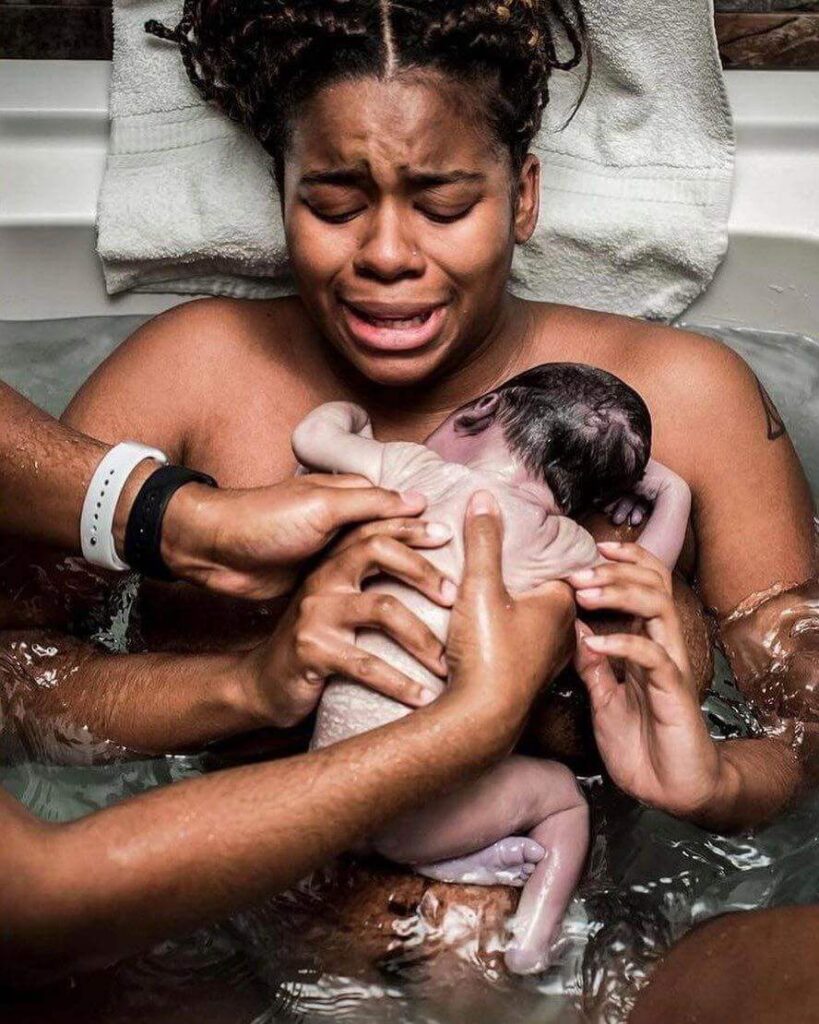 Woman being passed her newborn baby after giving birth in water